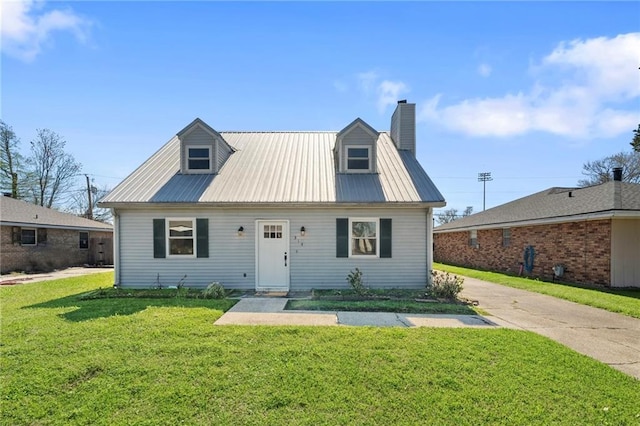 cape cod-style house featuring a chimney, metal roof, and a front yard