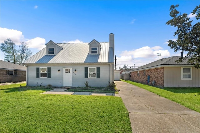 cape cod house featuring metal roof, driveway, a chimney, and a front lawn