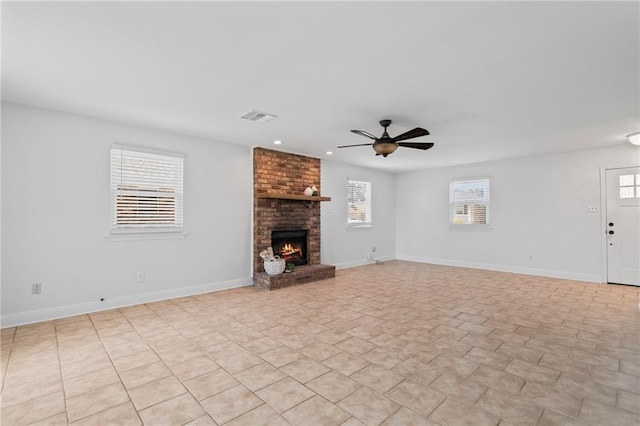 unfurnished living room featuring visible vents, a fireplace, a ceiling fan, and baseboards