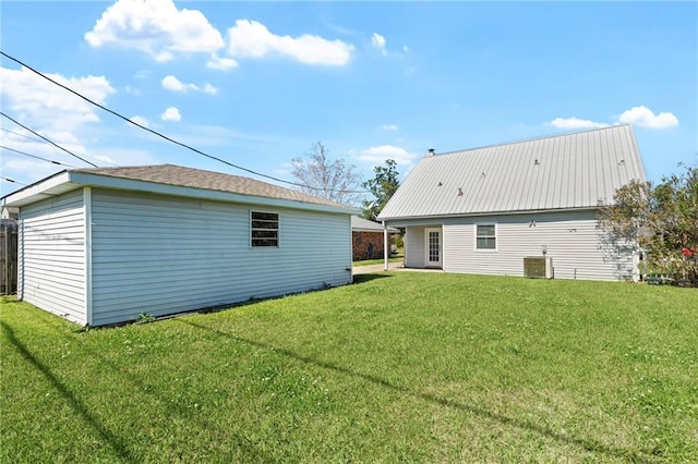 rear view of property featuring an outbuilding, a yard, and central AC unit