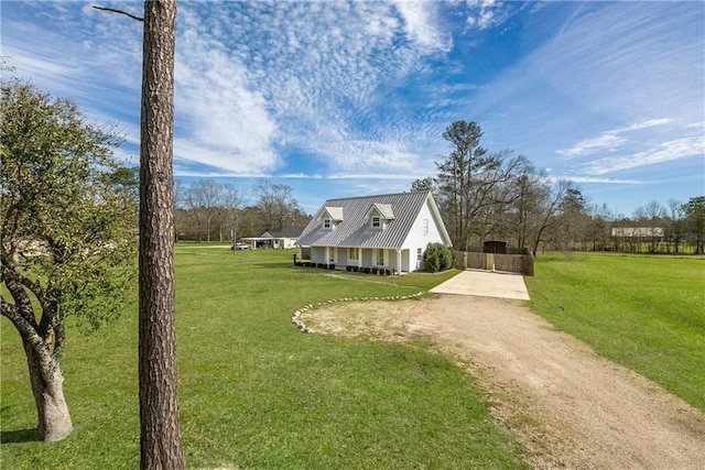 view of front of home with metal roof, a front yard, and dirt driveway