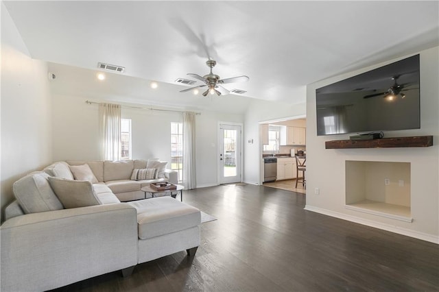 living room featuring baseboards, visible vents, dark wood-style flooring, and ceiling fan