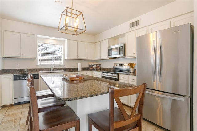 kitchen with a sink, stainless steel appliances, a kitchen breakfast bar, and white cabinetry