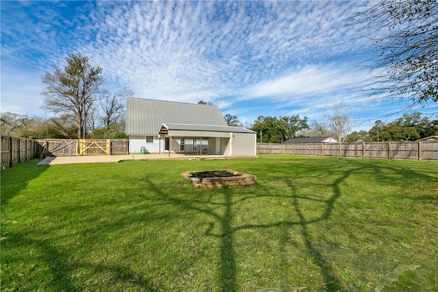 view of yard with an outbuilding, a fire pit, and a fenced backyard