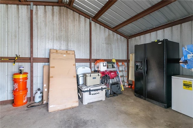 garage with black fridge, fridge, and metal wall