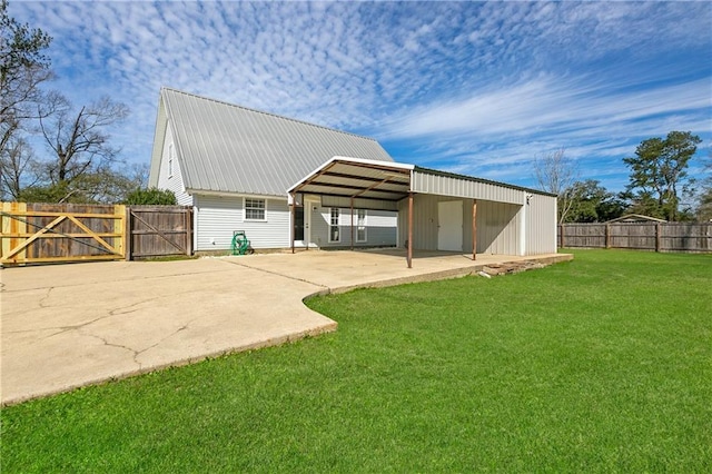 rear view of house featuring a gate, fence, a yard, metal roof, and a carport