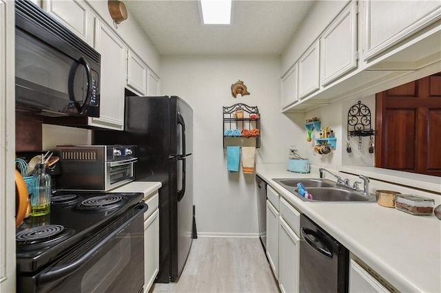 kitchen with light wood-style flooring, a sink, black appliances, white cabinets, and light countertops