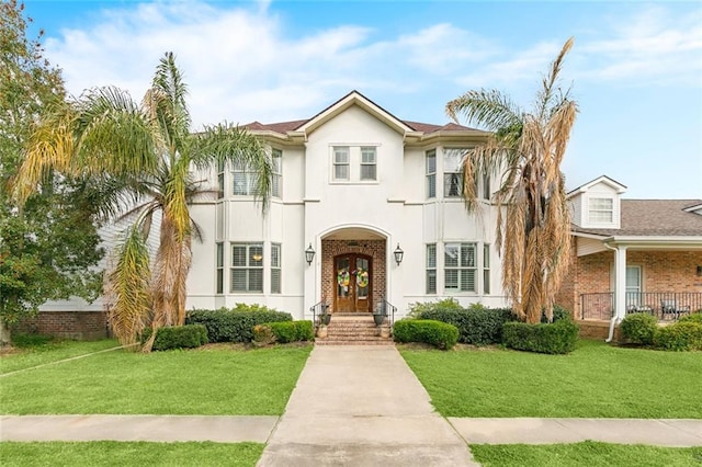 view of front facade featuring a front yard, french doors, and stucco siding