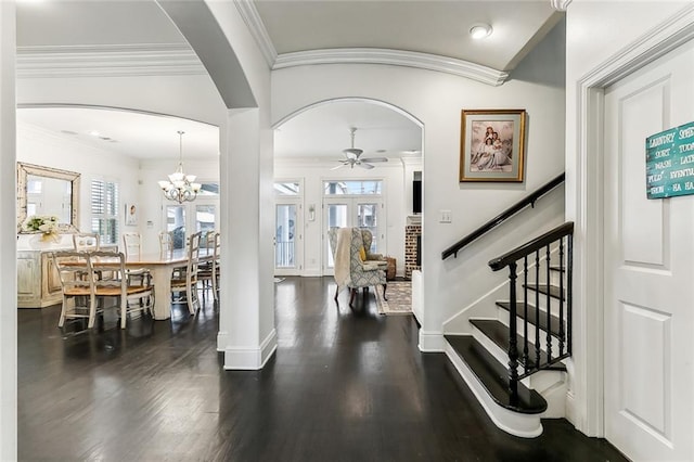 entrance foyer with crown molding, baseboards, dark wood finished floors, stairway, and arched walkways