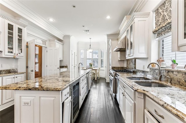 kitchen featuring a kitchen island with sink, a sink, white cabinets, high end stainless steel range oven, and crown molding