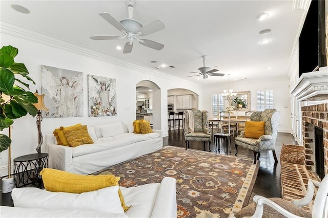 living area with wood finished floors, a fireplace, arched walkways, and ornamental molding