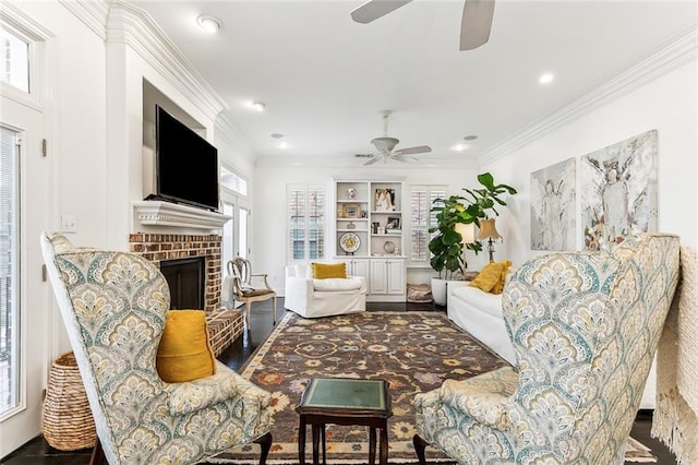 living area with recessed lighting, a brick fireplace, ornamental molding, and a ceiling fan