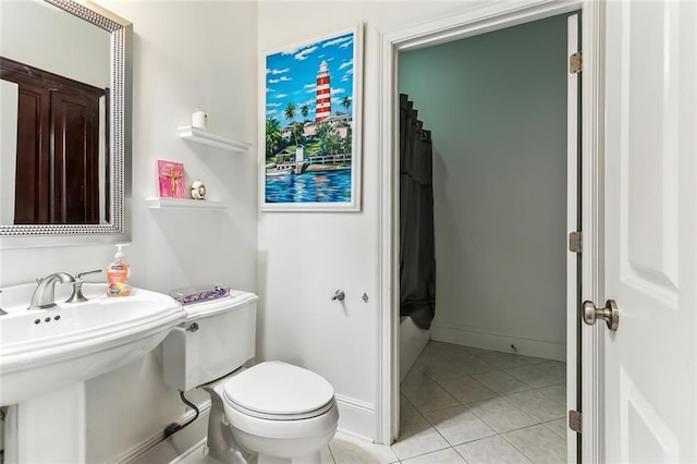 bathroom with a sink, baseboards, toilet, and tile patterned flooring