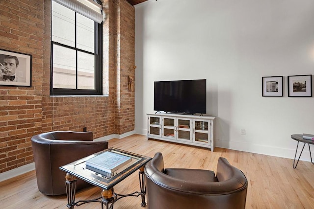 living room featuring baseboards, wood finished floors, and brick wall