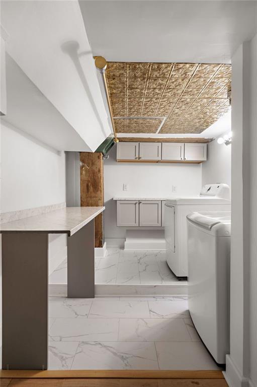 washroom featuring an ornate ceiling, marble finish floor, washing machine and dryer, and laundry area