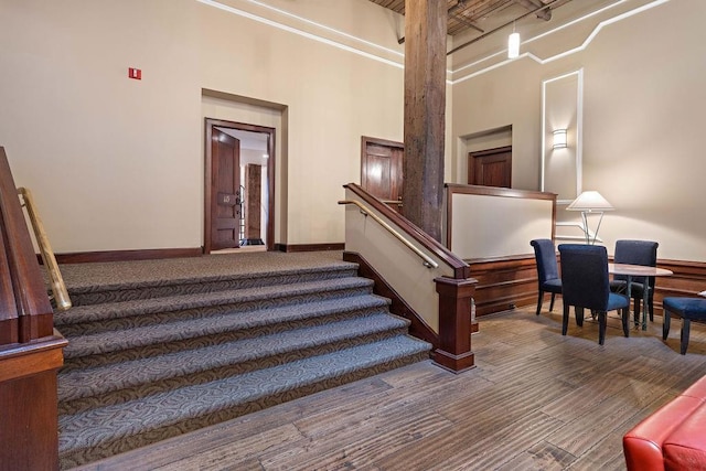 stairs with baseboards, a towering ceiling, and wood finished floors