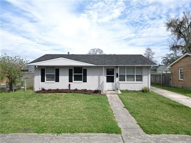 view of front of property featuring brick siding, a front lawn, and fence