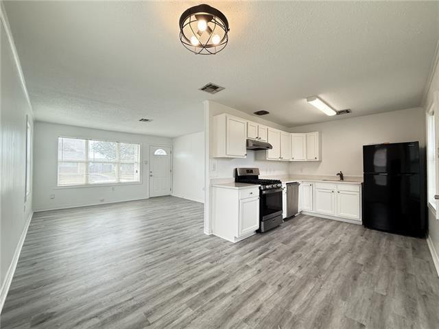 kitchen with visible vents, freestanding refrigerator, under cabinet range hood, range with gas cooktop, and open floor plan