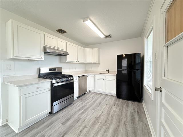 kitchen featuring light wood-style flooring, under cabinet range hood, appliances with stainless steel finishes, white cabinets, and light countertops