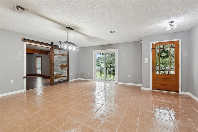 foyer with light tile patterned flooring, visible vents, and a barn door