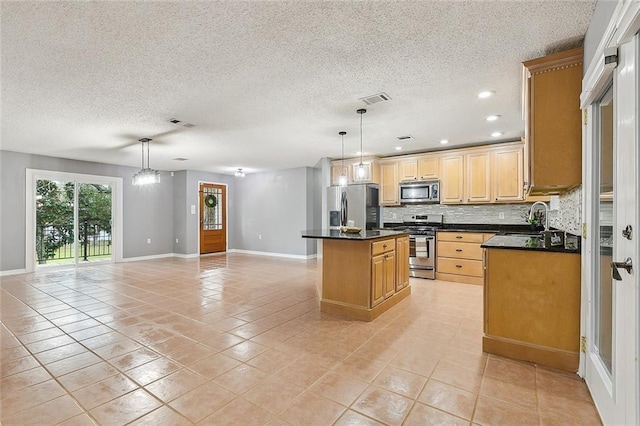 kitchen with visible vents, a sink, stainless steel appliances, backsplash, and a center island