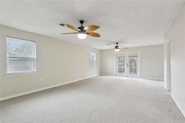 empty room with visible vents, baseboards, ceiling fan, light colored carpet, and a textured ceiling