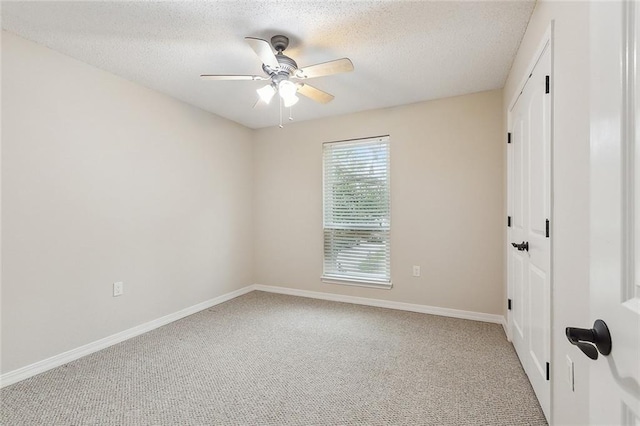 carpeted spare room featuring a textured ceiling, baseboards, and a ceiling fan