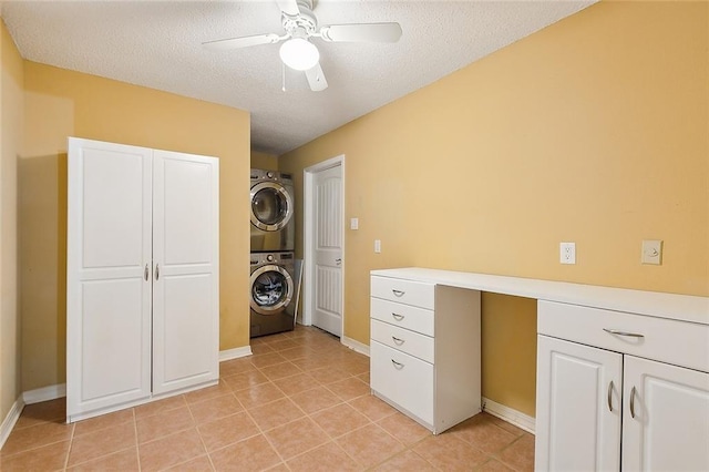 interior space featuring light tile patterned floors, baseboards, ceiling fan, a textured ceiling, and stacked washer / dryer