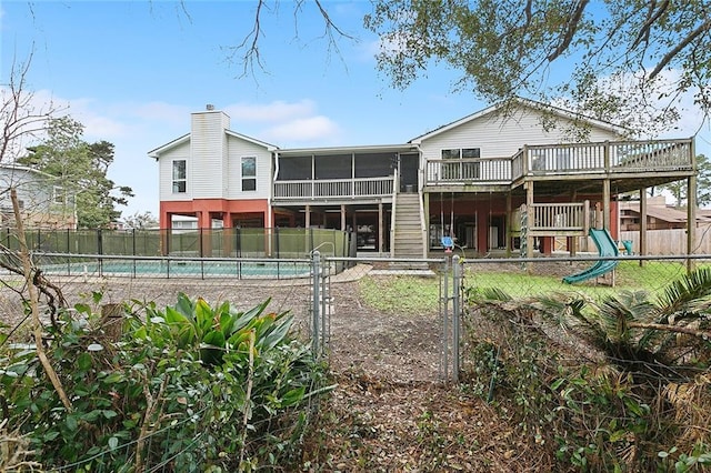 rear view of property featuring stairway, a sunroom, a fenced in pool, fence private yard, and a chimney