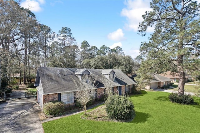 view of front of property with driveway, brick siding, and a front lawn