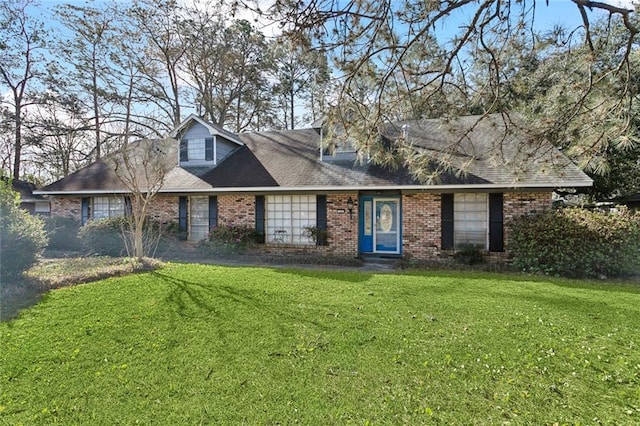 new england style home with brick siding, a front lawn, and a shingled roof