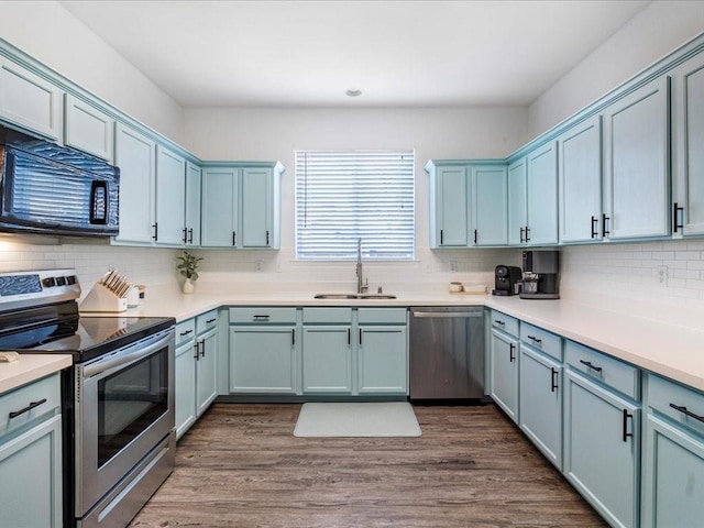 kitchen featuring dark wood-style flooring, backsplash, appliances with stainless steel finishes, and a sink