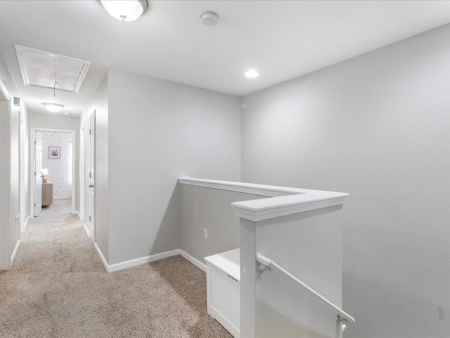 corridor with baseboards, an upstairs landing, light colored carpet, and attic access