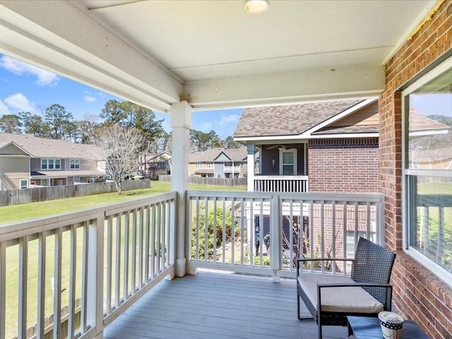 wooden deck featuring a residential view, a lawn, and fence