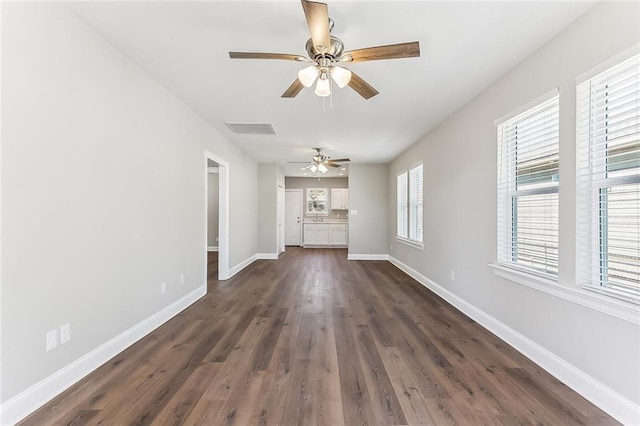 unfurnished living room with visible vents, baseboards, dark wood finished floors, and a ceiling fan