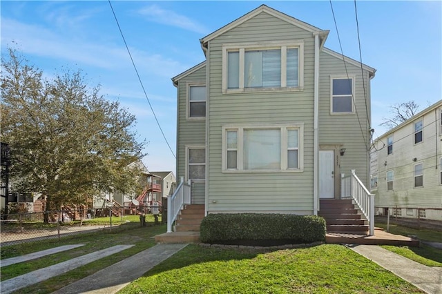 view of front of home featuring entry steps, a front yard, and fence