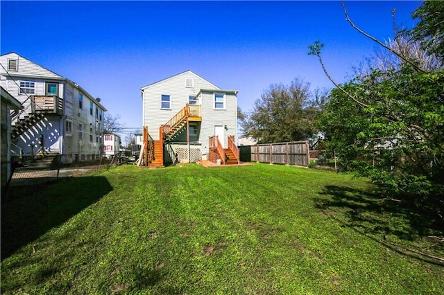 back of house featuring a lawn, stairs, and fence