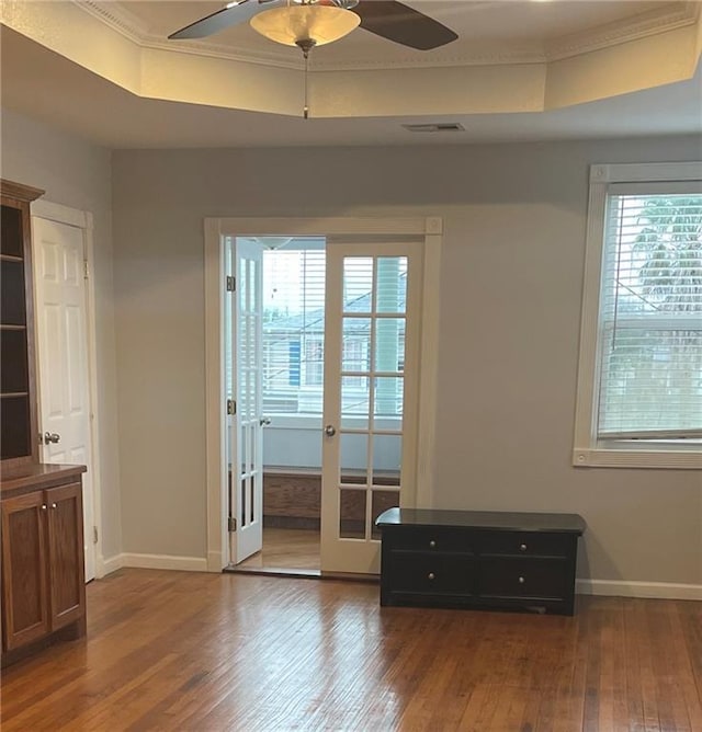 unfurnished room with a tray ceiling, visible vents, wood-type flooring, and ceiling fan