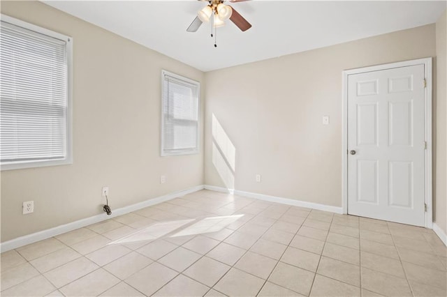 unfurnished room with light tile patterned flooring, baseboards, and a ceiling fan