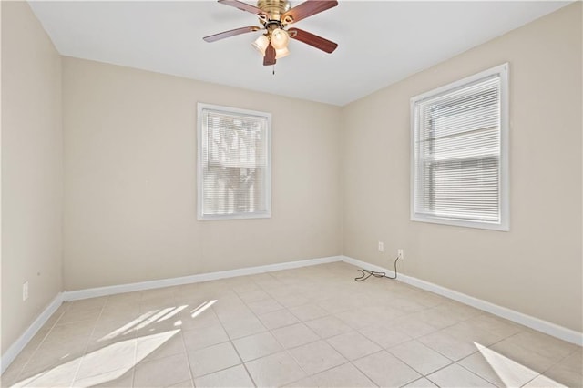 empty room with light tile patterned floors, a ceiling fan, baseboards, and a wealth of natural light