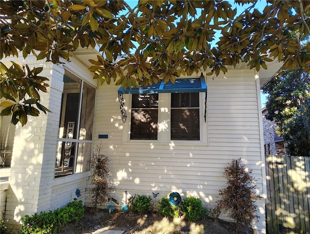 view of property exterior with brick siding and fence