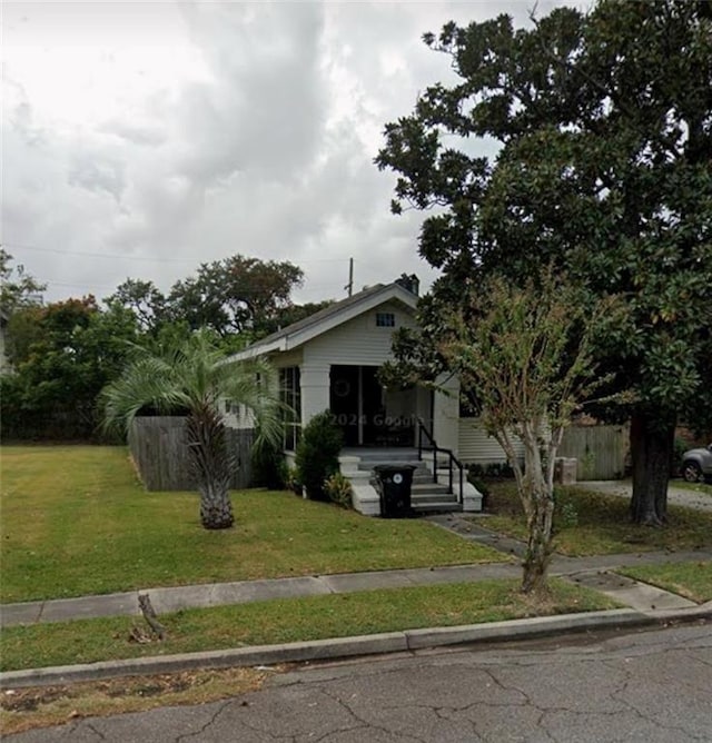 view of front of home with a front yard and fence