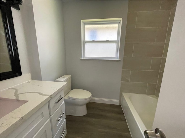 bathroom with baseboards, toilet, wood finished floors, and vanity