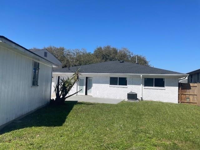 back of house with brick siding, a patio, a yard, and fence