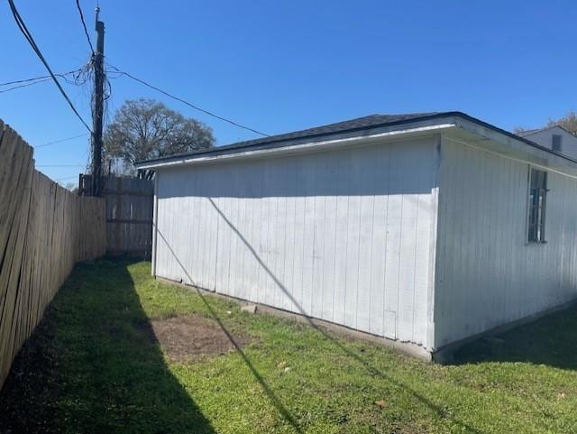 view of property exterior featuring a yard, an outdoor structure, and fence