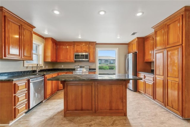 kitchen with visible vents, a sink, a kitchen island, appliances with stainless steel finishes, and brown cabinetry