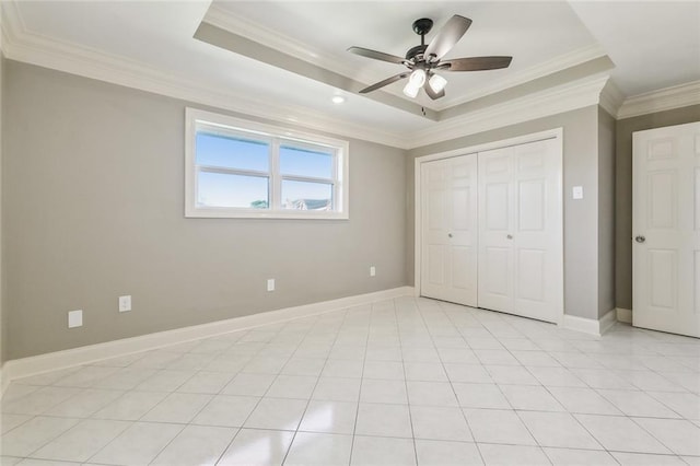 unfurnished bedroom with light tile patterned flooring, a raised ceiling, baseboards, and ornamental molding