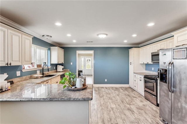 kitchen featuring light wood finished floors, stainless steel appliances, crown molding, and a sink