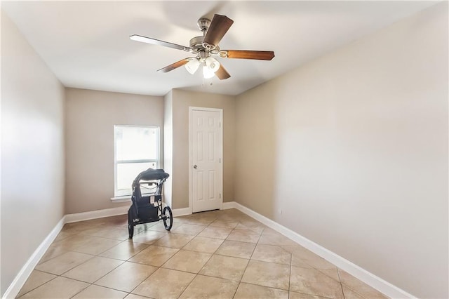 unfurnished room with light tile patterned floors, a ceiling fan, and baseboards