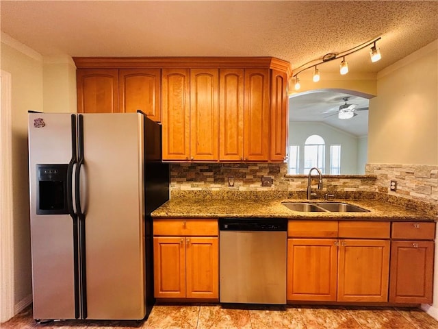 kitchen featuring brown cabinetry, arched walkways, appliances with stainless steel finishes, and a sink